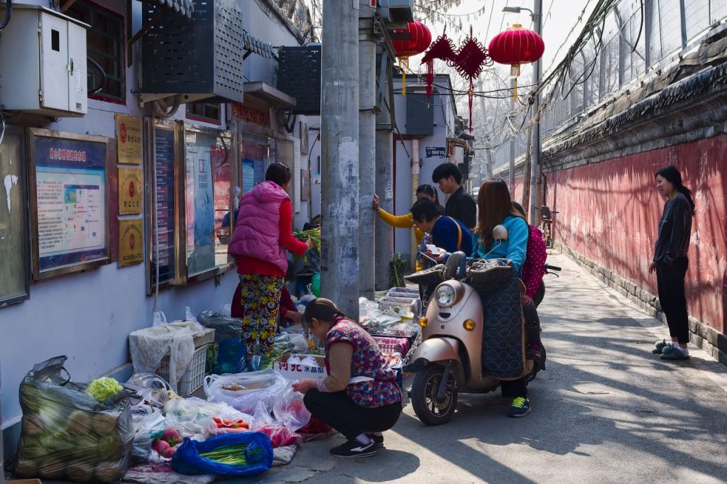 Explore a colorful street market in a Beijing hutong, showcasing local vendors and fresh produce. Visiter la Chine pour la première fois